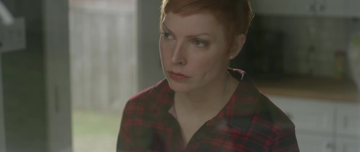 A woman sitting in a kitchen casts her eyes up