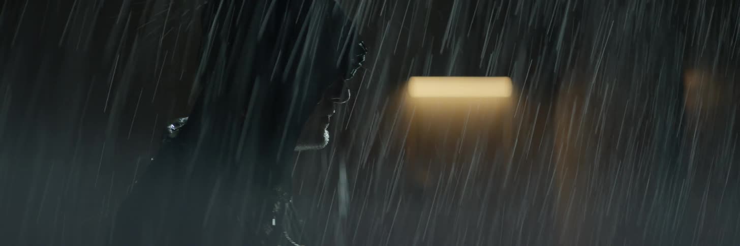 A man stands outside in the rain at night