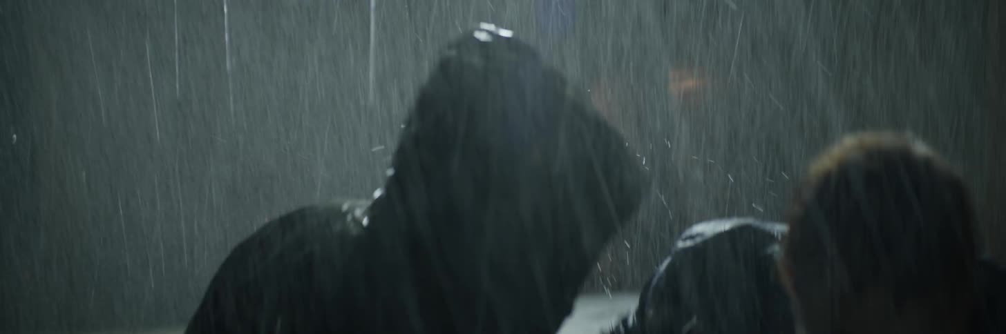 Two people fight each other in the rain at night