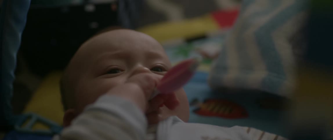 Baby chews on a plastic toy and waves its arms