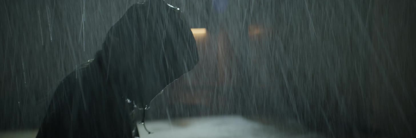 Two people fight each other in the rain at night