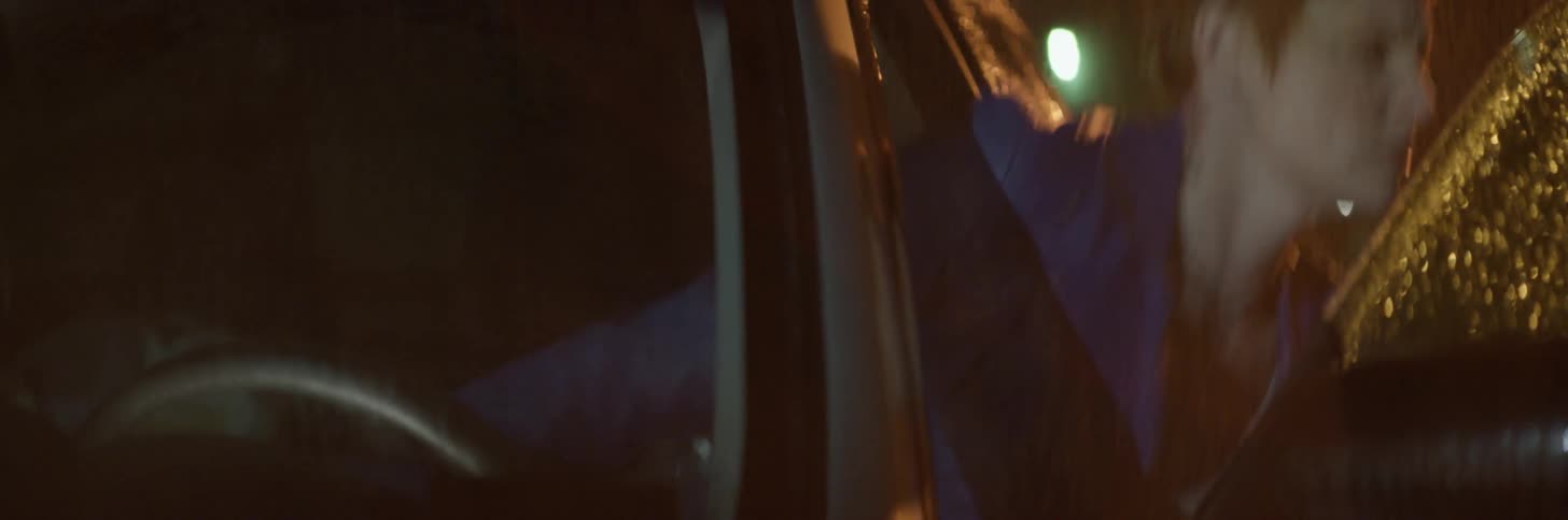 A woman gets out of her vehicle on a rainy night