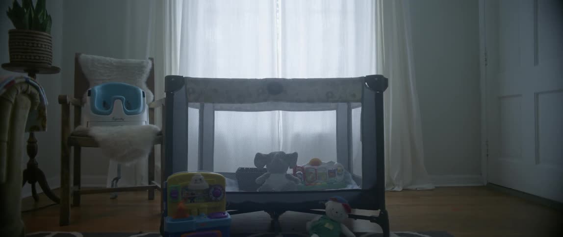A pack and play is shown with toys all around