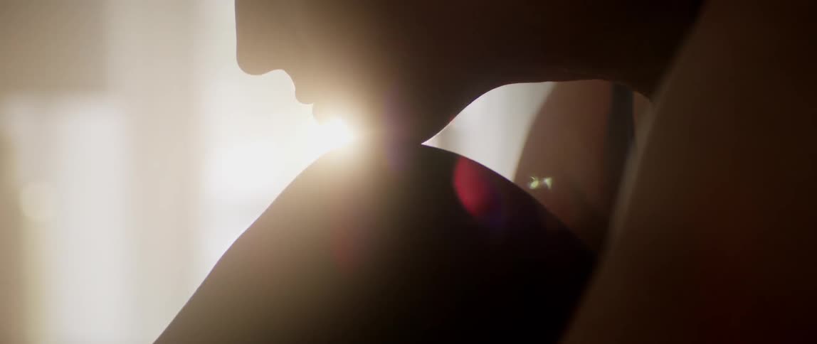 A person rests their chin on their knee with the sun shining behind them