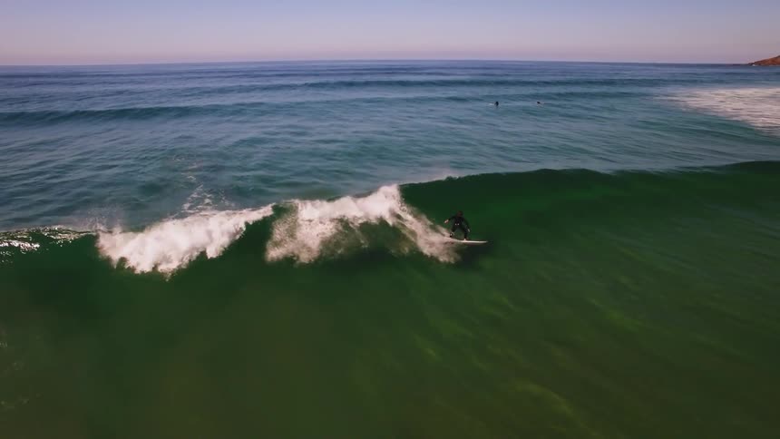 Surfer balancing and standing up on surfboard on a wave in the ocean