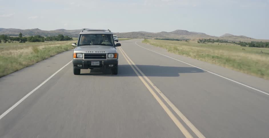 Jeep drives down a country road on a sunny day