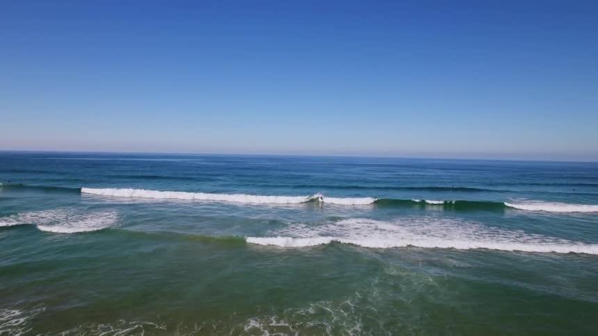 View of waves crashing to shore and a person surfing