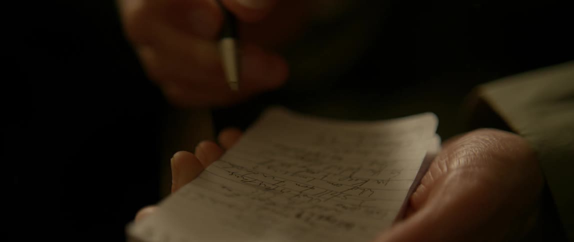 A woman writes in a small notepad with a pen
