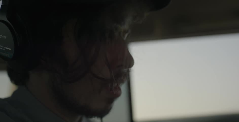 A man rides in a car while wearing headphones