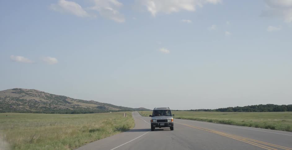 A land rover drives on a rural road