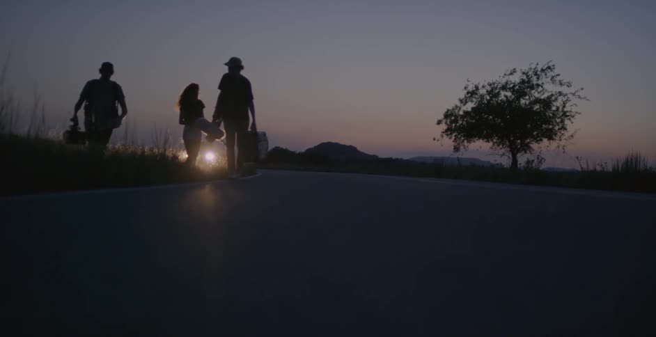 People walk forward at dawn in front of a car light