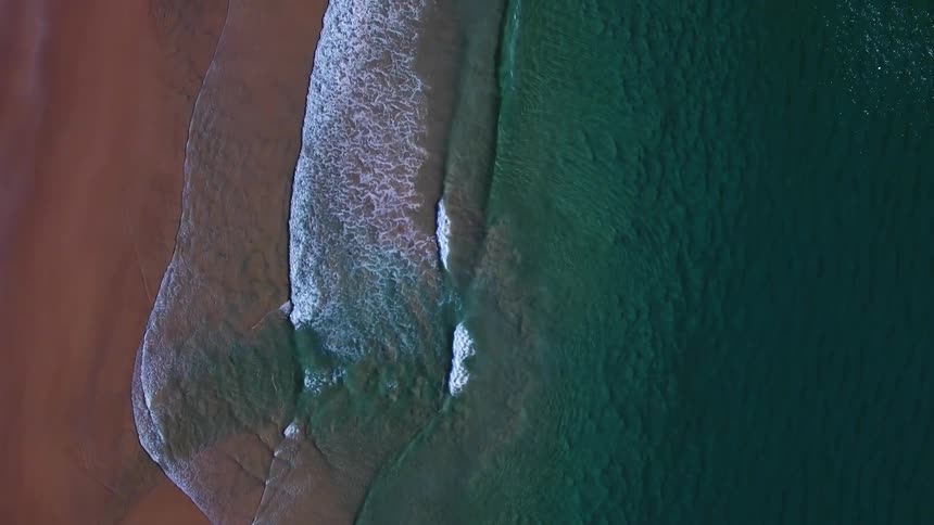 The small waves slowly move onto the sand below