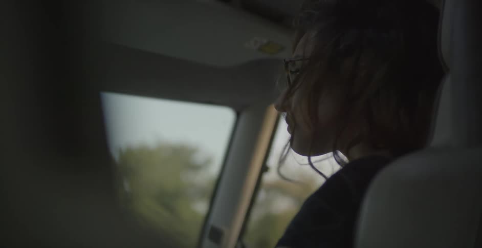 A woman is sitting in the passenger side of a vehicle while travelling