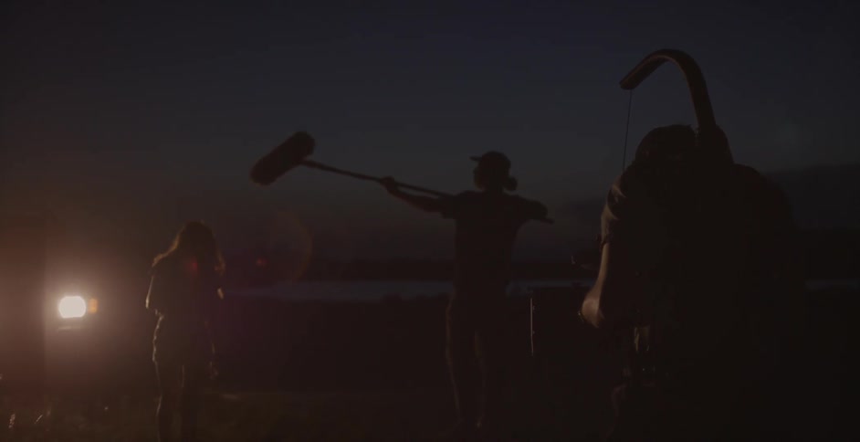 A woman is standing outside at night as she is filmed