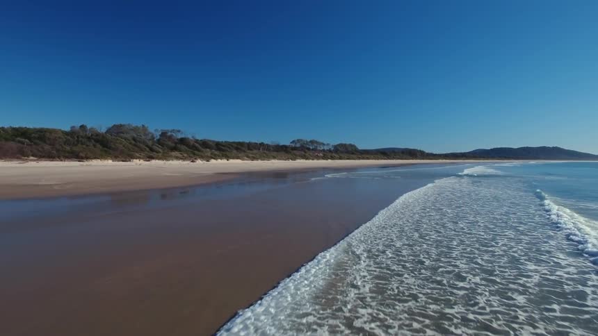 The beach has blue water hitting the shore slowly
