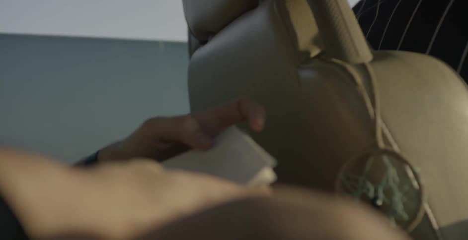 A man sitting in the backseat of a vehicle is going over storyboard drawings