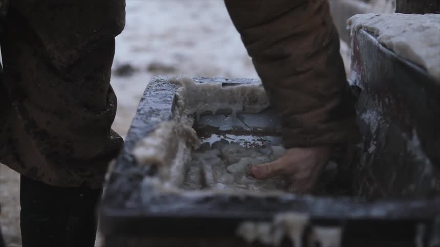 A man scoops ice and debris out of a water container