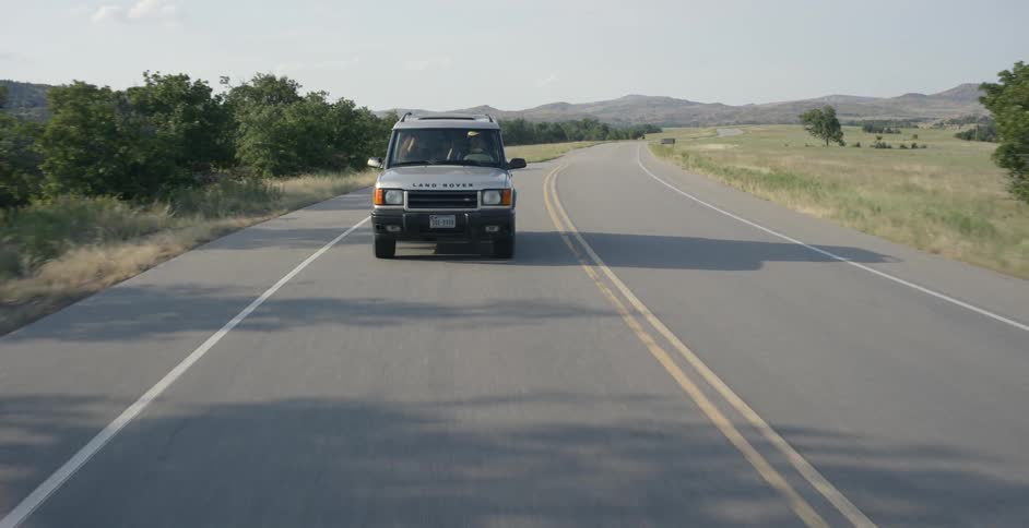 Jeep drives down a country road on a sunny day