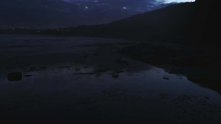 A lake surrounded by hills at night