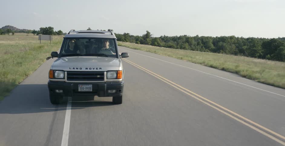 Jeep drives down a country road on a sunny day