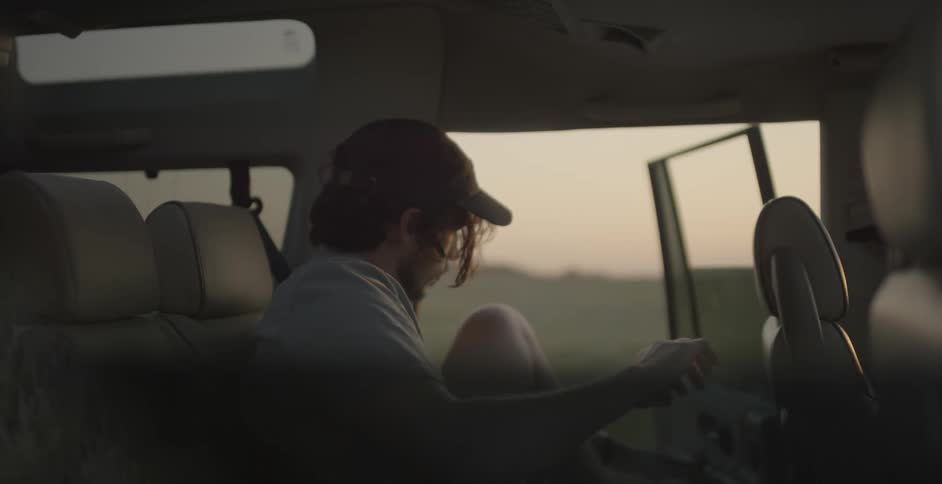 A man removes his headphones and quickly exits an suv