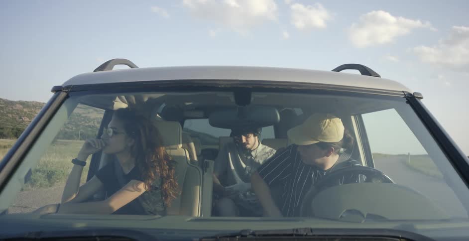 Woman and two men wait in a jeep for another man to get in the jeep