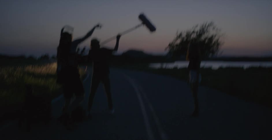 A few men standing on the road at night filming something