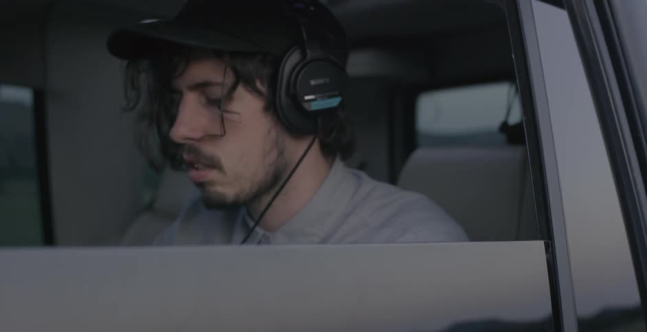 A man with headphones inside a car looking down
