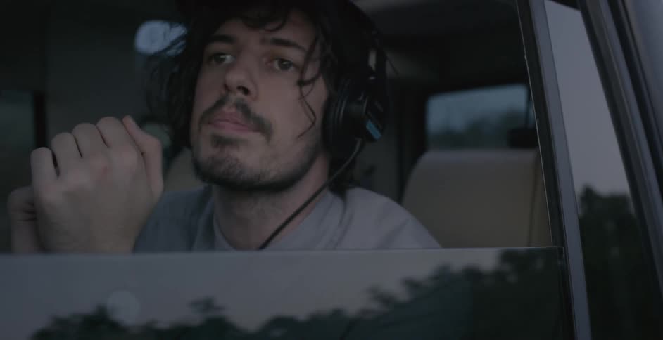 A man in a car looking around as he rides on the back