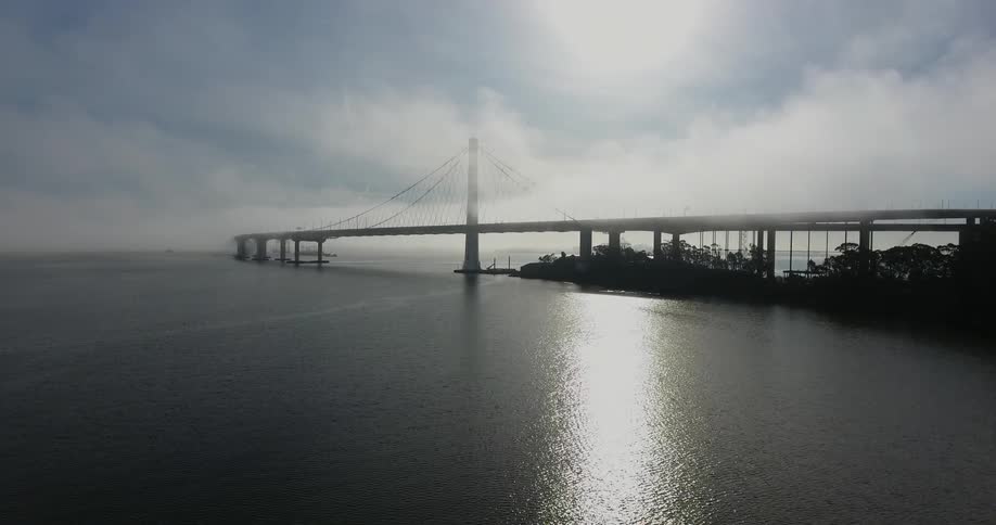 A long bridge is covered with fog on a cloudy day