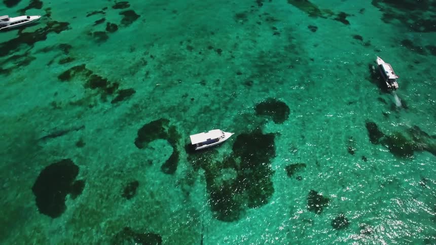 Boats float on the ocean on a sunny day