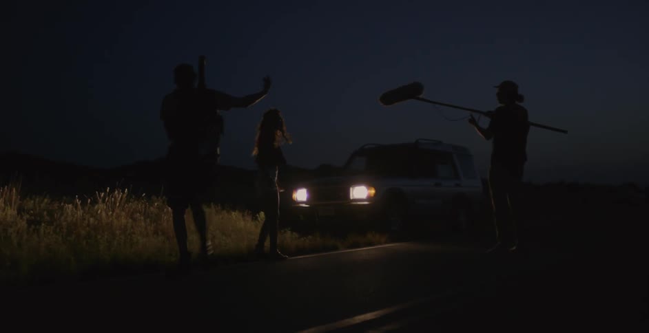 A woman is recorded by a film crew in a rural area at night