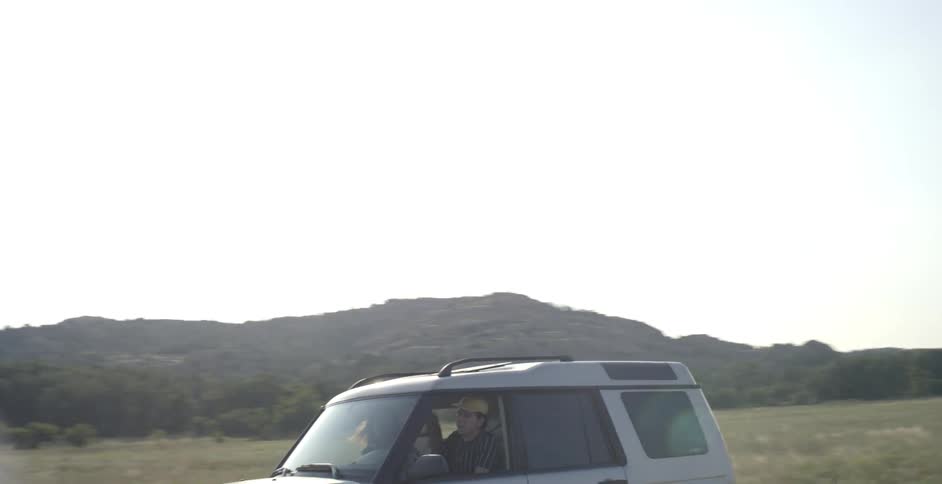 A gray land rover drives with its blinker on