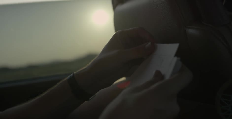 A person is flipping through notes in a car