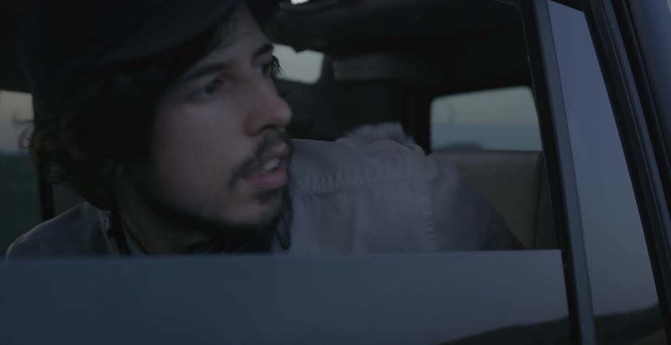 A man takes his headphones off while riding in a car