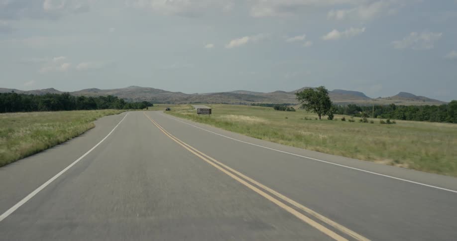 A single vehicle is moving down the road in the distance