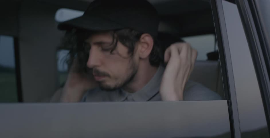 A man in a car with headphones looking down at something