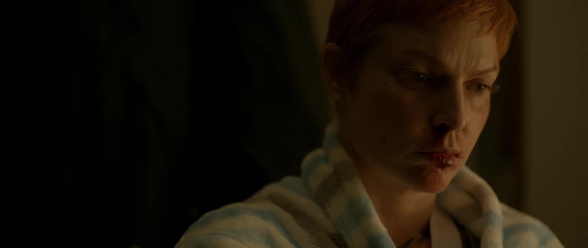 A woman with short hair sits as a man passes her