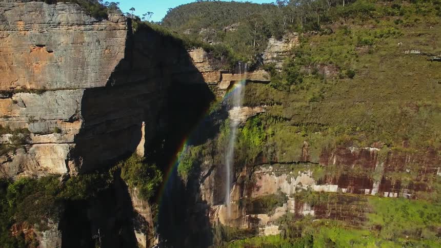 Rainbow shining off a waterfall on a cliff