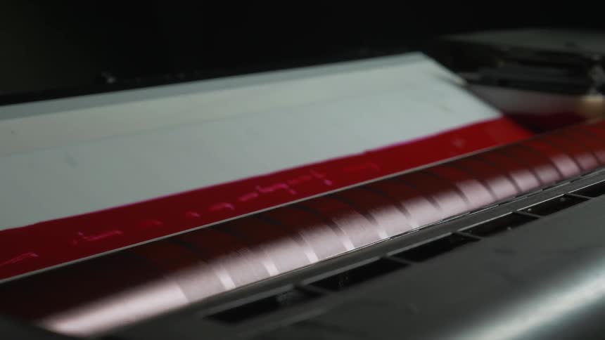 A machine rolling red strips out onto paper