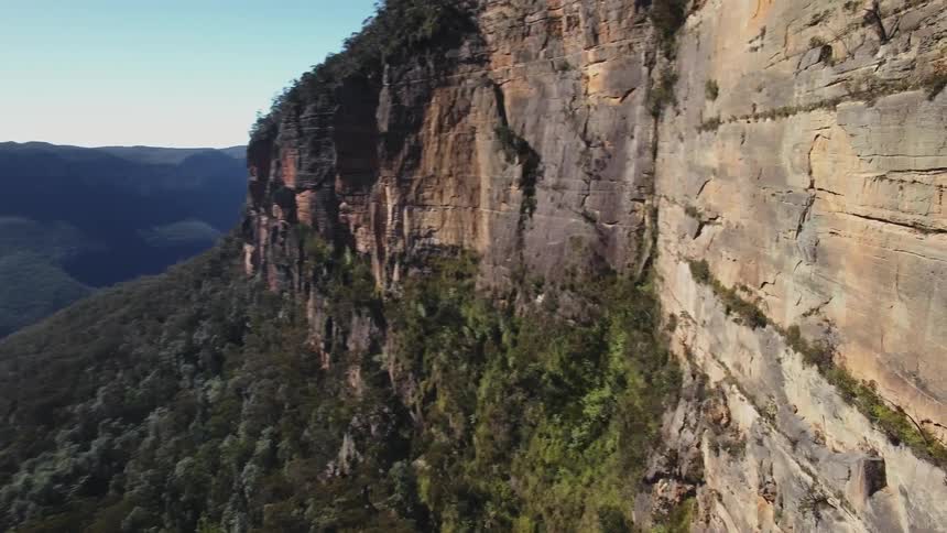 Tree covered mountains and cliff on a sunny day