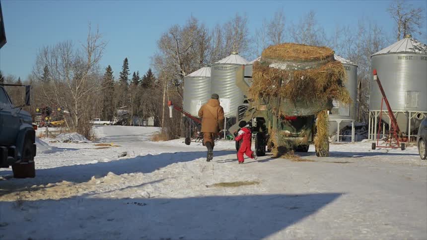 Man and child run through a farm yard covered in snow