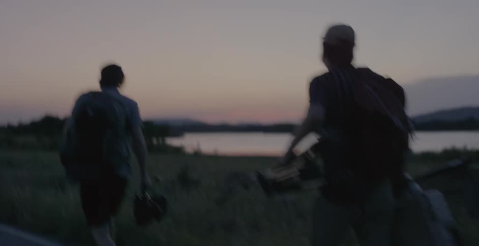 Group of people walking down a country road near a lake at dusk