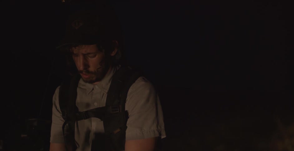 A cameraman gestures to direct action as a crew films at night