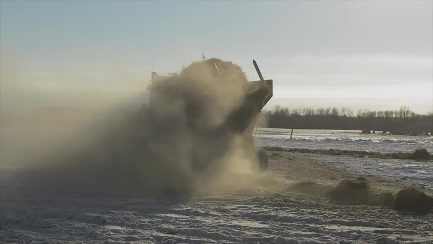 Tractor surrounded by dust in the middle of a snowy field