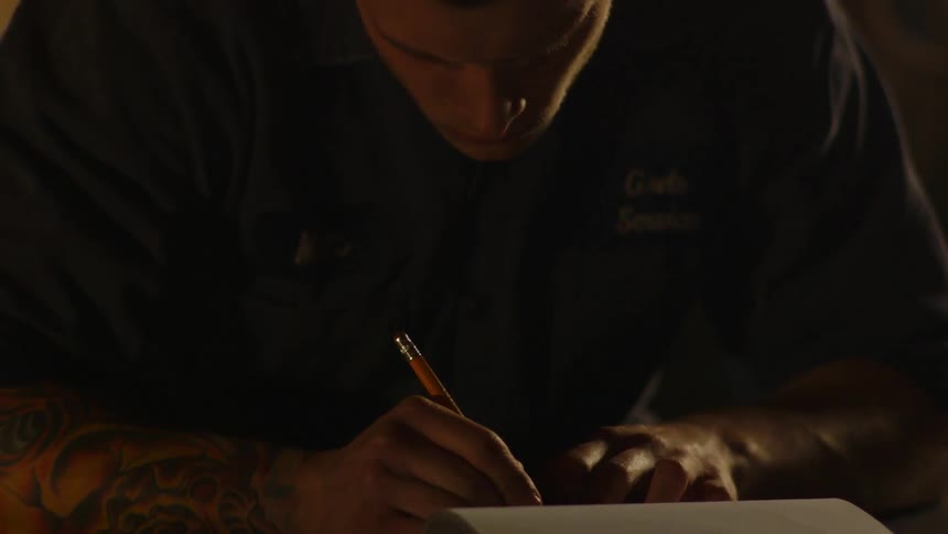 A man is writing with a pencil in the dark