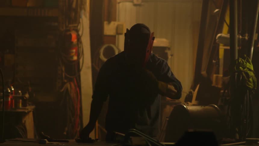 A man puts on a welding mask and gloves