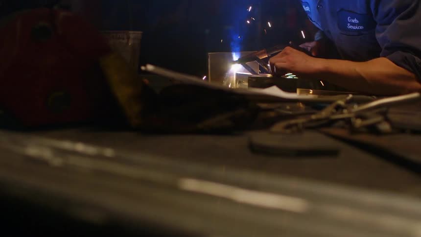 A man working on something inside a shop with a grinder