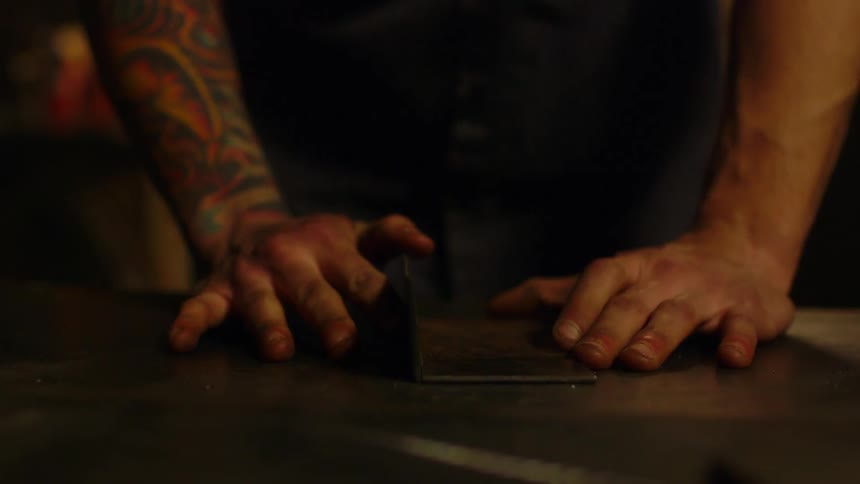 Man measures a piece of metal on a desk