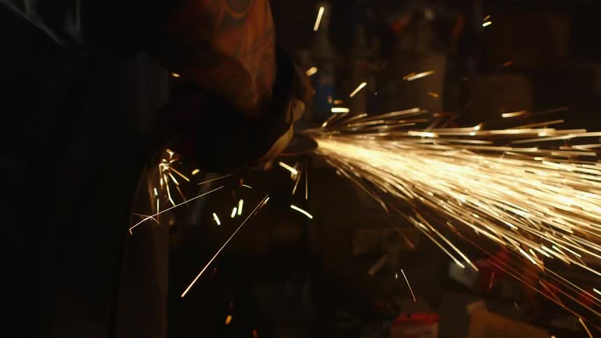 A man working on something inside a shop with a grinder